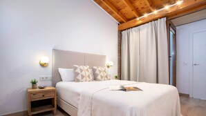 Un dormitorio con cama, mesita de noche, luces fijadas a la pared y una puerta.