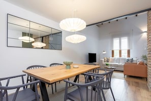 Een eethoek met een houten tafel, grijze stoelen en hanglampen.
