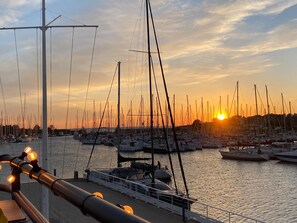 En lysthavn med flere både i havnen, en klar himmel og en solnedgang.