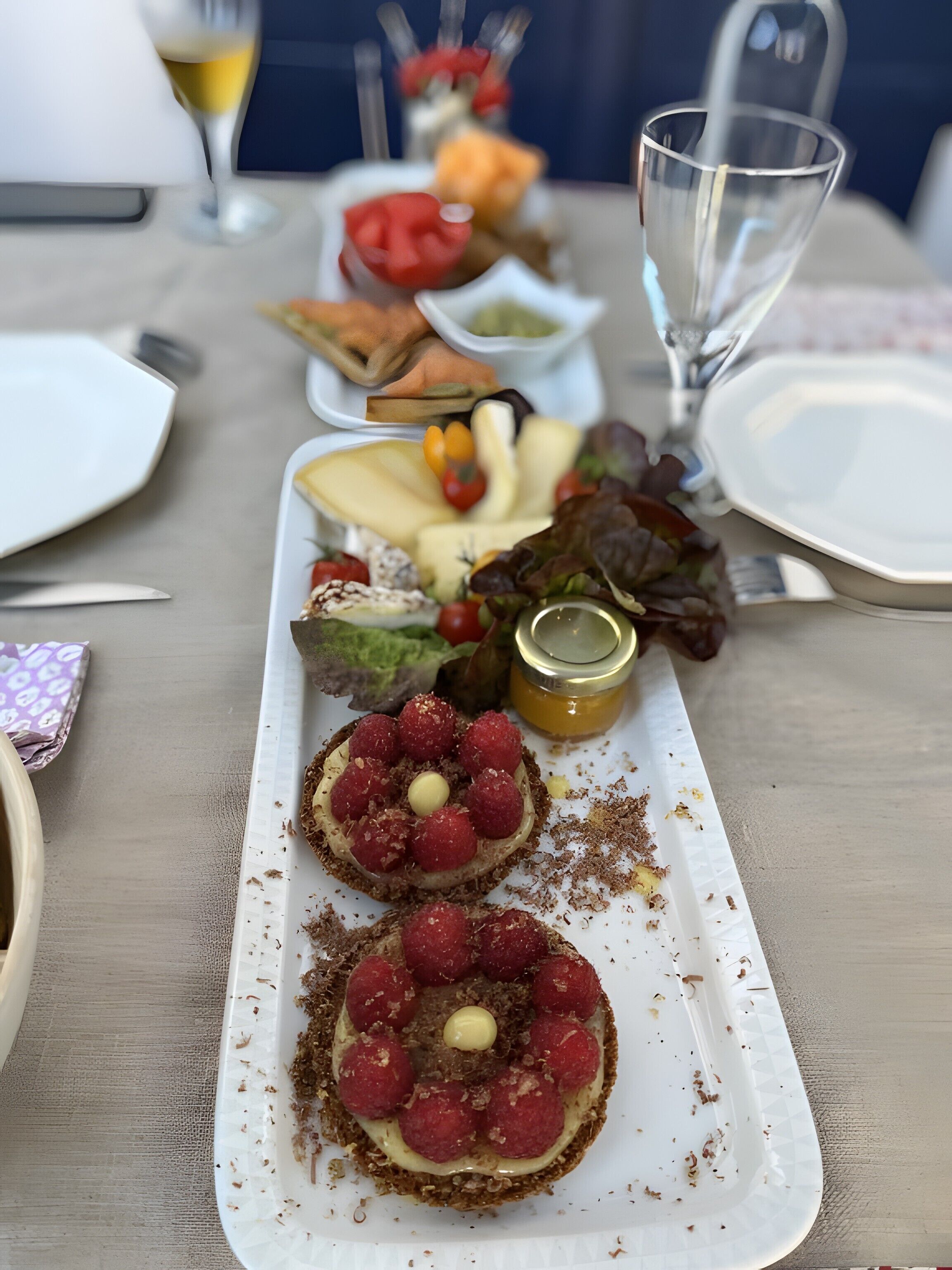 Een eettafel met een bord eten, een glas witte wijn en een saladeschaal.