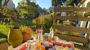 A picnic setup with food and drinks on a table, surrounded by a garden with various plants and a wooden fence. - Bed and Breakfast 'Chambre 1 Coté Plage' with Private Terrace, Shared Garden and Wi-Fi (Arzon)