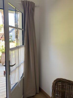 Una habitació amb una porta corredissa de vidre, una cadira de vimet i una paret blanca.
