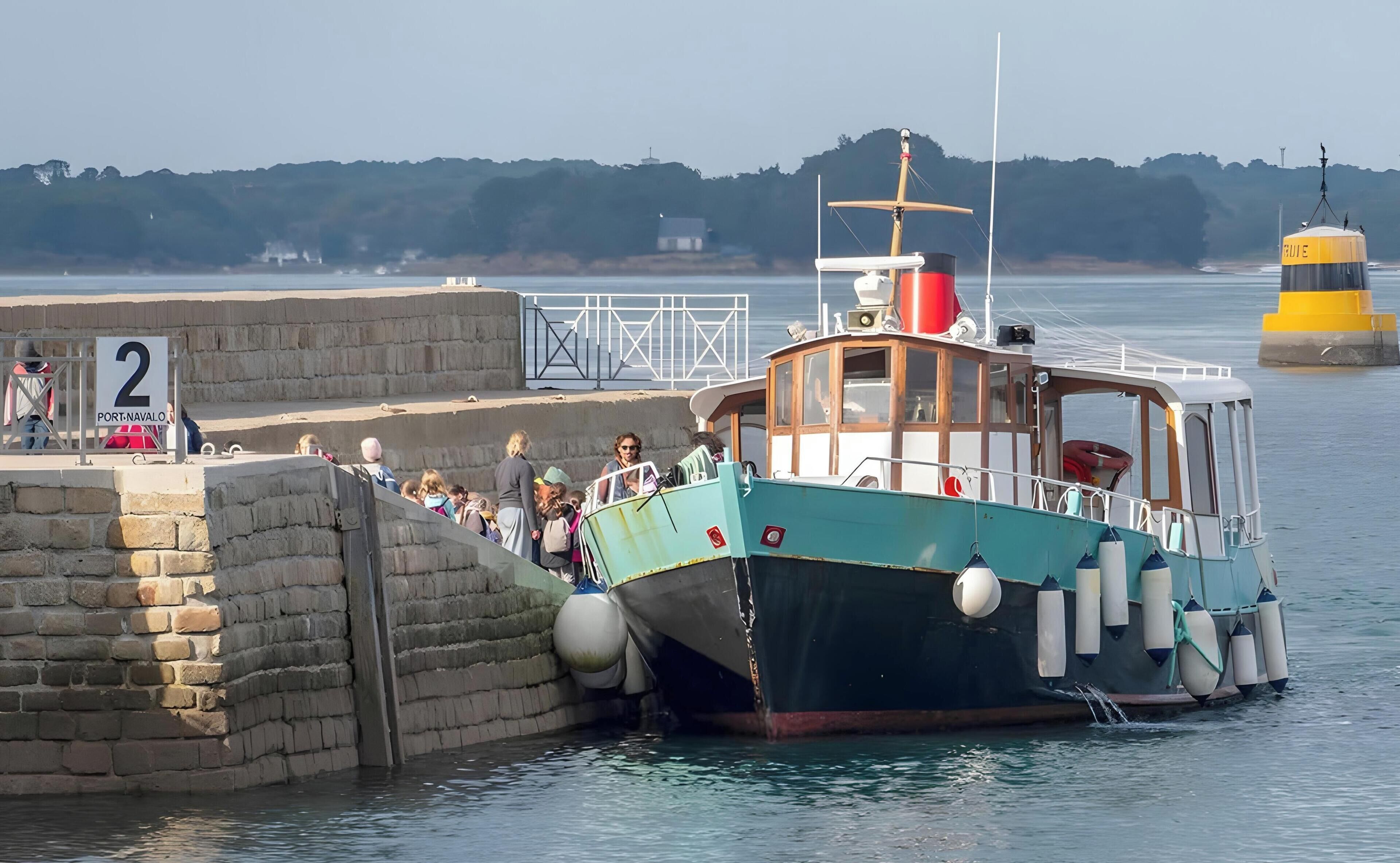 Un bateau était amarré à un quai bordé d’un mur de pierres, et une pancarte indiquait « Port-Naval ».