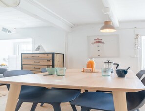 Eine moderne Küche mit einem Holztisch, schwarzen Stühlen, einer Kaffeemaschine und einem Saftspender.