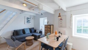 A modern interior with a dining area, sofa, and a view of greenery outside. - House in Porspoder by Plage du Bourg Beach (Porspoder)