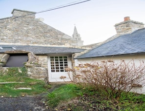 A stone building with a white door, a small window, and a chimney. - House in Porspoder by Plage du Bourg Beach (Porspoder)