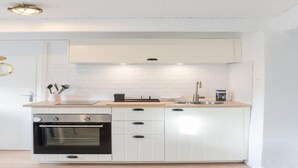 A modern kitchen with white cabinetry, a stainless steel oven, a sink, and a countertop with a few items. - House in Porspoder by Plage du Bourg Beach (Porspoder)