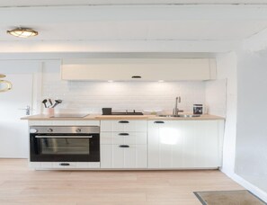 Eine moderne Küche mit weißen Schränken, einem Edelstahlbackofen, einer Spüle und einer Arbeitsfläche mit einigen Gegenständen.