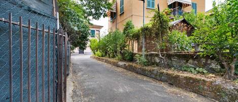 Une rue étroite bordée d’immeubles dotés de balcons, d’une clôture en métal et de verdure.