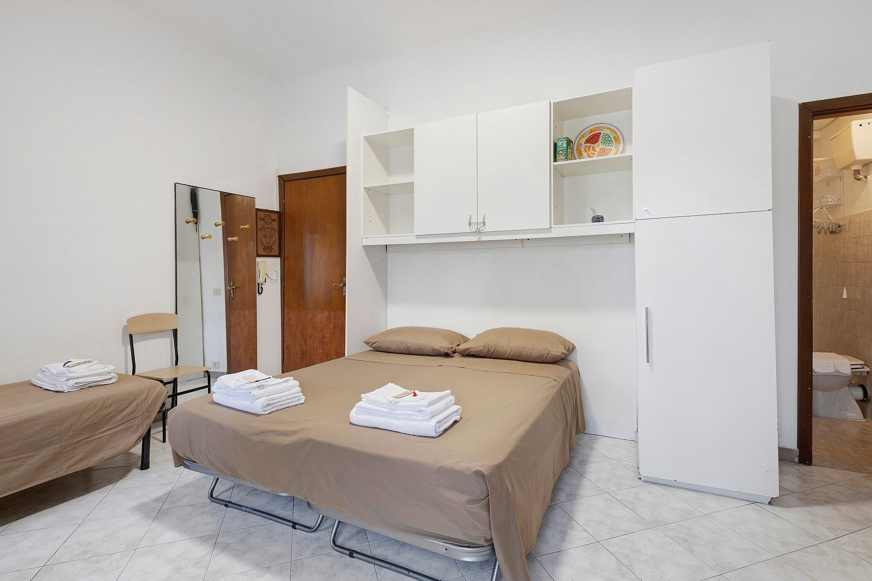 Une chambre d’hôtel avec un lit, une chaise, une armoire et une salle de bain.