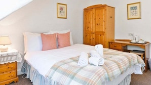 Una camera da letto con un letto, un'armadio in legno, una scrivania con una sedia e un comodino con una lampada.