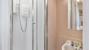 Un bagno con doccia vetrata, un lavandino bianco e uno specchio.