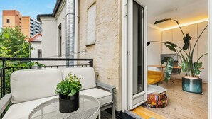 A balcony with a white sofa, a small round table with a plant, and a potted plant on the floor. - Light apartment with rooftop views in Tøyen (Oslo)