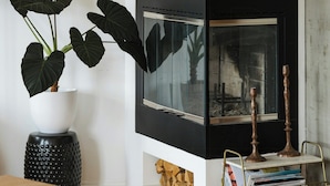 A modern kitchen with a large window, a potted plant, and a fireplace. - Light apartment with rooftop views in Tøyen (Oslo)