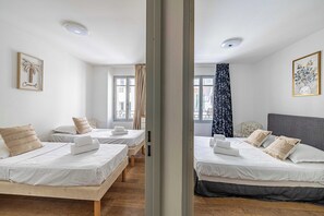 Ein Hotelzimmer mit zwei Betten, einem Fenster mit Vorhängen und einem gerahmten Bild an der Wand.