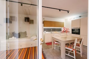 A modern kitchen with wooden cabinets, a dining table, and a built-in oven. - Scalone XVI Ottobre | Dimora con cortile privato (Verona)