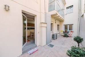 A residential building with a glass door entrance, a small patio with a table and chairs, and a potted plant. - Scalone XVI Ottobre | Dimora con cortile privato (Verona)