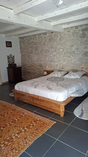 Ein Schlafzimmer mit Steinsturz, einem hölzernen Bett, einem Nachttisch, einer Lampe und einem gemusterten Teppich.