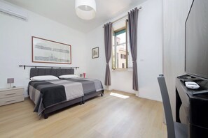 A bedroom with a bed, bedside table, lamp, and a window with curtains. - 4BNB - DAquino Apartment close to Vatican Museums (Rome)