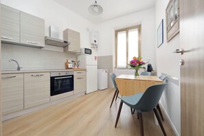 Una cucina moderna con forno integrato, microonde e frigorifero, un tavolo da pranzo con sedie e una finestra con vista.