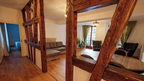 Un amplio salón con vigas de madera, un sofá y una mesa de comedor.