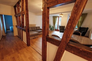 A spacious living area with wooden beams, a sofa, and a dining table. - La Cure Apartment (Wintzenheim)