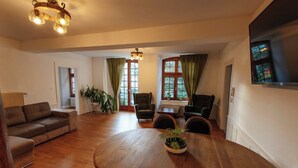 Un salón espacioso con mesa de comedor de madera, asientos cómodos y ventanas grandes con cortinas.