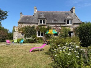 A two-story house with a garden, outdoor seating, and a flag. - Charming Coastal Stone House With Garden (Landunvez)