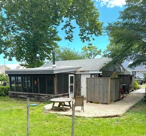 A house with a covered patio, a fenced yard, and a vehicle parked outside. - Welcome to Little Bit O' the Bay (Saint Leonard)