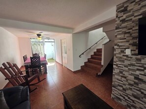 A living room with a dining area, a staircase, and a view of the outside. - Just 15 minutes from Antigua Guatemala, within the La Joya Condominium. (Santa Lucía Milpas Altas)