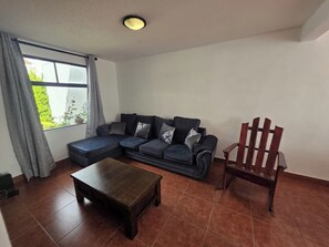 Ein Wohnzimmer mit einem Ecksofa, einem Couchtisch aus Holz und einem Holzstuhl.