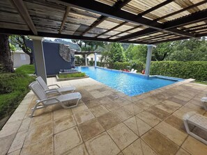 A covered outdoor swimming pool with lounge chairs and a stone feature wall. - Just 15 minutes from Antigua Guatemala, within the La Joya Condominium. (Santa Lucía Milpas Altas)