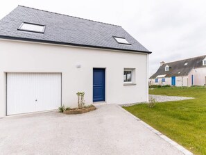 A single-story building with a garage, a blue door, and a small window. - Charming Coastal Home in Landunvez (Landunvez)