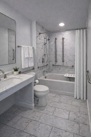 Un baño moderno con suelo de mármol, bañera, ducha, inodoro y lavabo.
