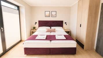 Een slaapkamer met een groot bed, een nachtkastje, een kledingkast en een schuifdeur.'