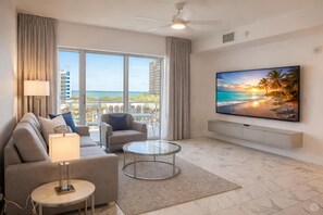 A modern living room with a sofa, armchair, glass coffee table, and a flat-screen TV. - Bay  and  City Corner Escape (Clearwater)