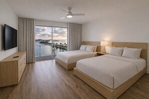 A hotel room with two beds, a TV, a desk, and a view of the water. - Bright Bay View 2BR Corner Suite (Clearwater)