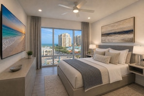 Een moderne hotelkamer met een groot bed, een plafondventilator, uitzicht op de stad en een schilderij aan de muur.