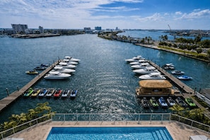 A marina with boats docked, a pool, and a view of the city skyline. - Bright Bay View 2BR Corner Suite (Clearwater)