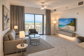 Ein modernes Hotelzimmer mit Balkon, einem Flachbildfernseher, einem Sofa, einem Couchtisch und einer Lampe.