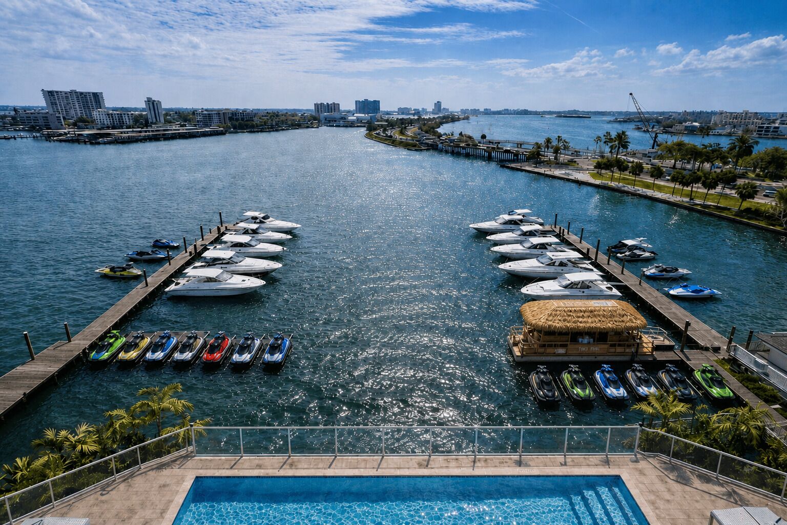 A marina with boats docked, a pool, and a view of the city skyline.