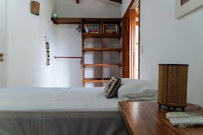 Ein Schlafzimmer mit einem Bett, einer Holzregal, einer Lampe und einem Nachttisch.