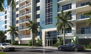 Un hôtel à plusieurs étages au design moderne, doté de balcons, de grandes fenêtres et d’un aménagement paysager de style tropical.