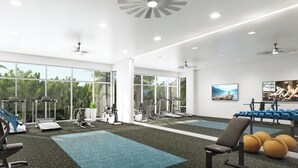Une salle de sport équipée de machines de cardio, de matériel de musculation et dotée de grandes fenêtres.