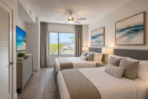 Une chambre d’hôtel avec deux lits, un ventilateur de plafond, une grande fenêtre donnant sur un beau paysage et des œuvres d’art accrochées aux murs.
