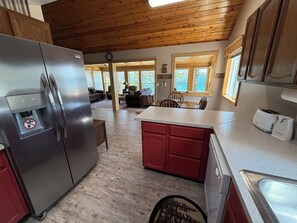 Eine Küche mit Kühlschrank, ein Essbereich mit Tisch und Stühlen sowie ein Wohnzimmer mit Sofa.