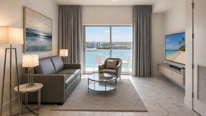 Ein modernes Wohnzimmer mit Sofa, Sessel, Couchtisch und Fernseher an der Wand.