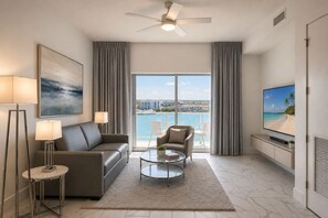 A modern living room with a sofa, armchair, coffee table, and a TV on a wall. - Waterfront Penthouse Residence (Clearwater)