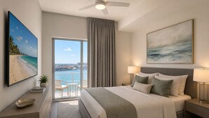 Ein Hotelzimmer mit Bett, Meerblick, Deckenventilator und einem Gemälde.