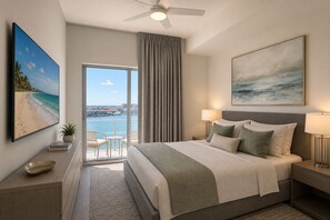 A hotel room with a bed, a view of the sea, a ceiling fan, and a painting. - Waterfront Penthouse Residence (Clearwater)